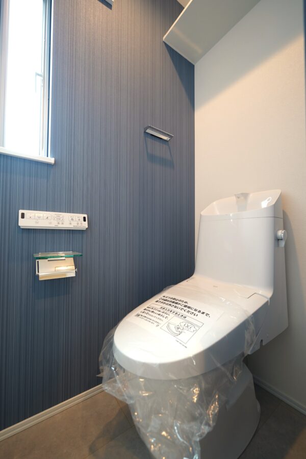 落ち着いたブルーグレーの壁が印象的なトイレ空間。シンプルなデザインの中に上品さがあり、窓からの自然光が心地よく差し込みます。(内装) 落ち着いたブルーグレーの壁が印象的なトイレ空間。シンプルなデザインの中に上品さがあり、窓からの自然光が心地よく差し込みます。(内装)